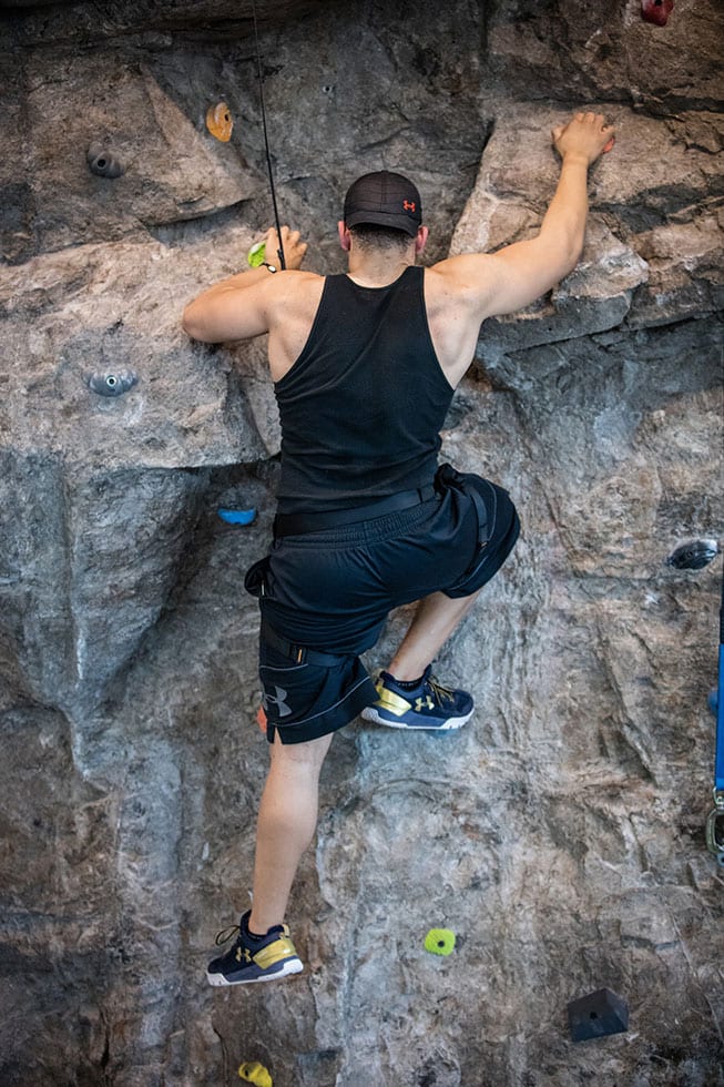 man using skills and strength climbing up indoor rock wall at ashburn va gym